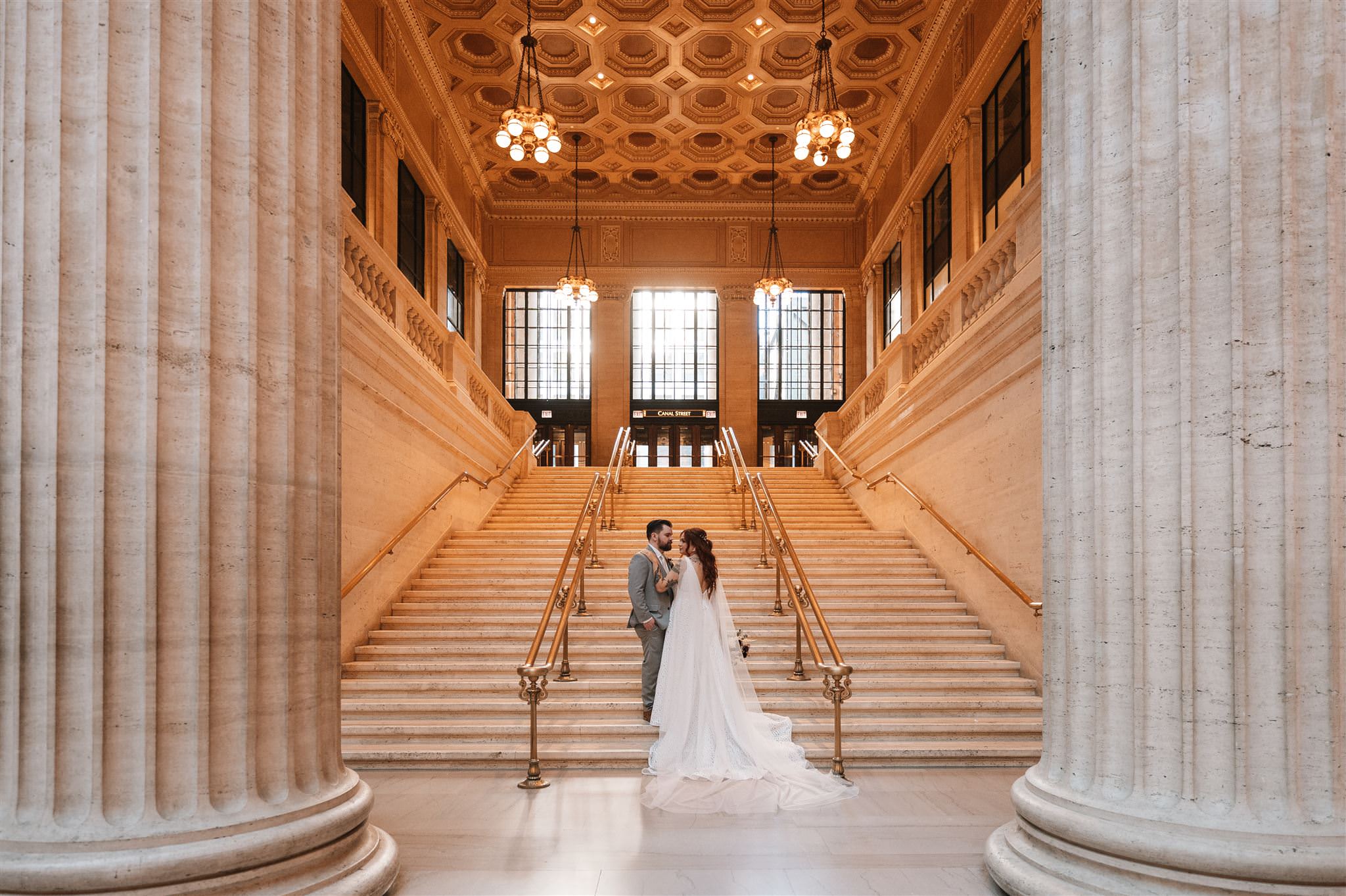 bride and groom stand on a grand staircase at Union Station in downtown Chicago, Il. Photo by Melissa Ferrara Photography