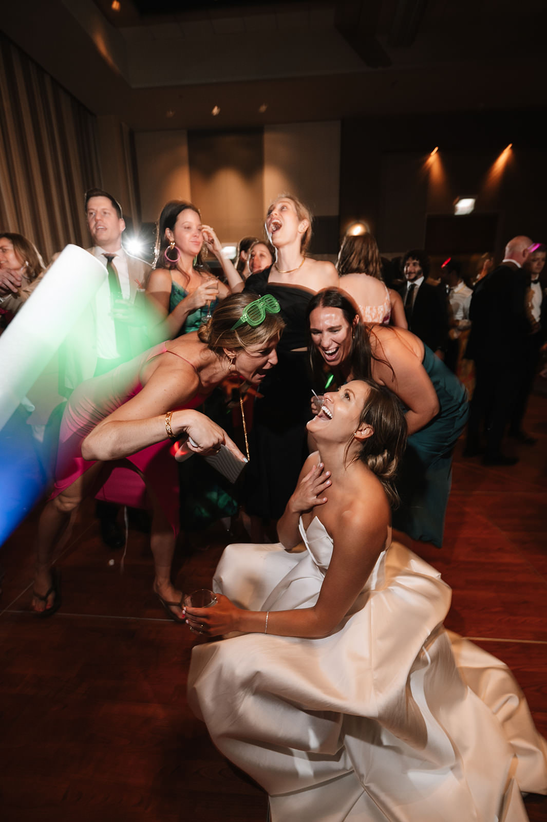 Candid wedding reception dance floor moment with guests laughing and celebrating