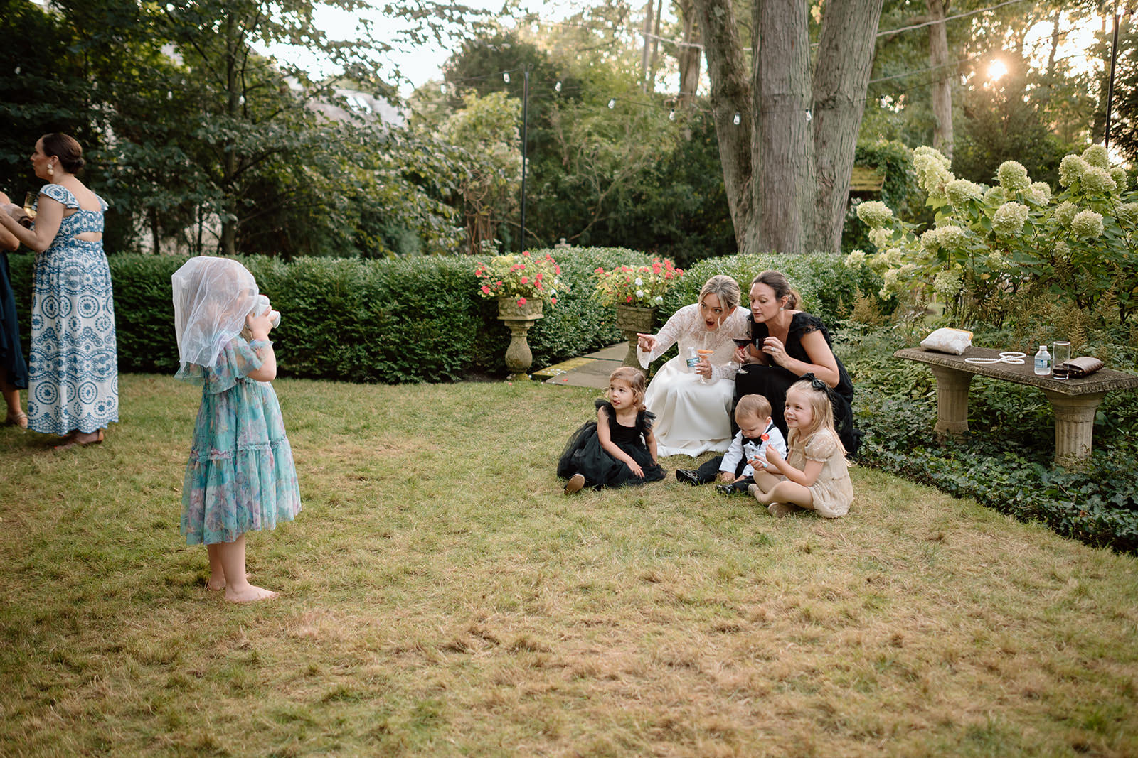 Wedding photography styles example showing a candid documentary moment of a bride sitting with children during cocktail hour