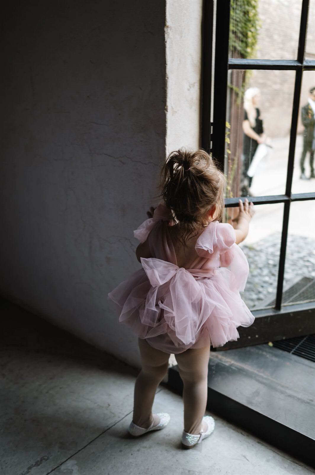 Quiet documentary wedding moment of a child watching the ceremony through a window